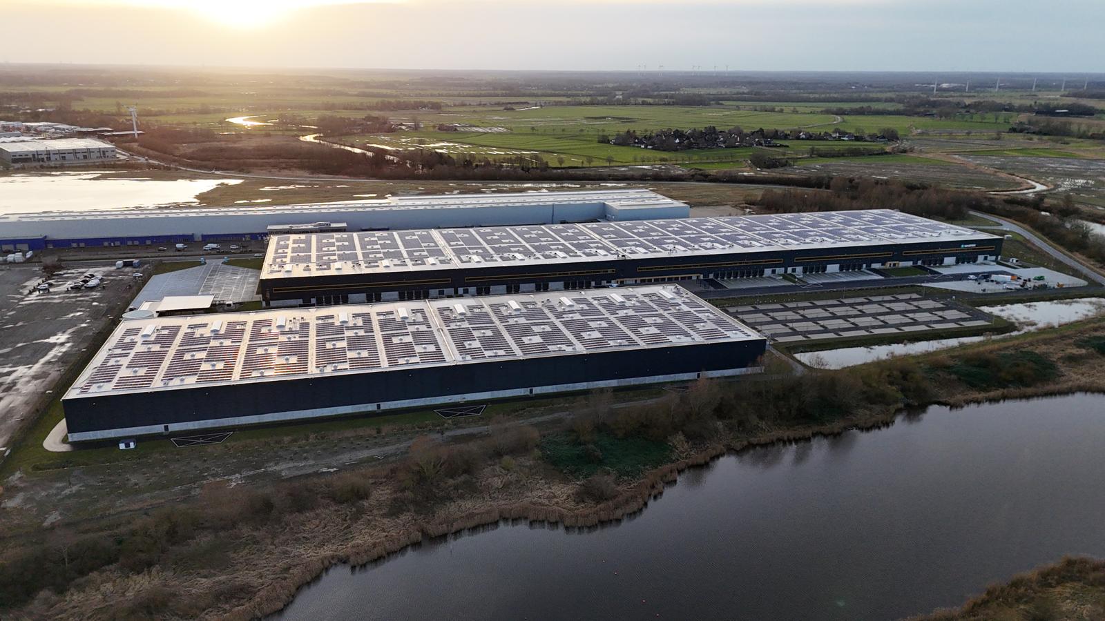 Luftaufnahme der drei Hallenkomplexe mit Photovoltaikanlage bei Abendlicht